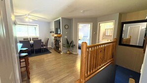 A spacious living area with a dining table, chairs, a fireplace, and a staircase. - Fernie - Riverside Way 1230 (Fernie)