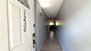A hallway with a door marked '1230', a light fixture, and a view into a room at the end. - Fernie - Riverside Way 1230 (Fernie)