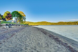 Ranta, jossa on kivimuuri, puita ja tyyni järvi.