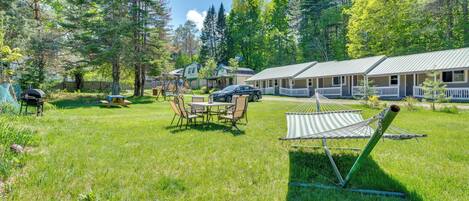 A grassy area with a hammock, a picnic table, and a barbecue grill.
