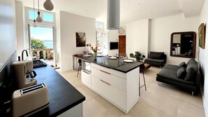 Eine moderne Küche mit Kochinsel, einem Essbereich inklusive Sofa und einem großen Spiegel.
