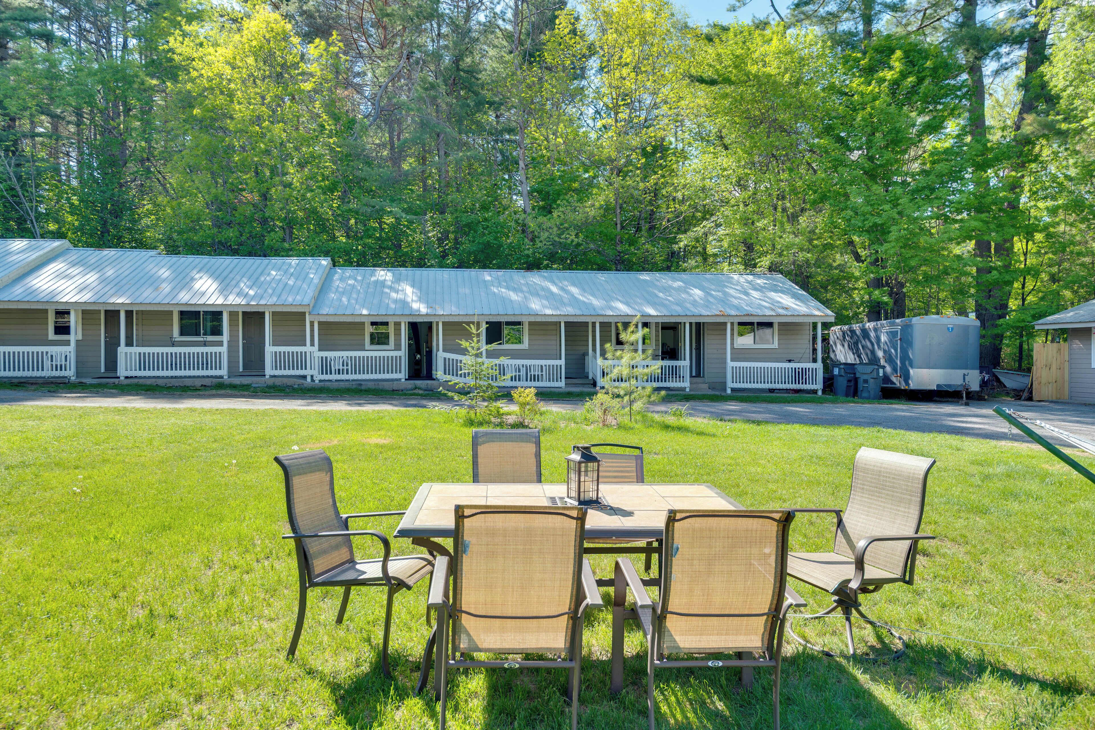 A motel with a grassy lawn, outdoor seating, and a covered parking area.