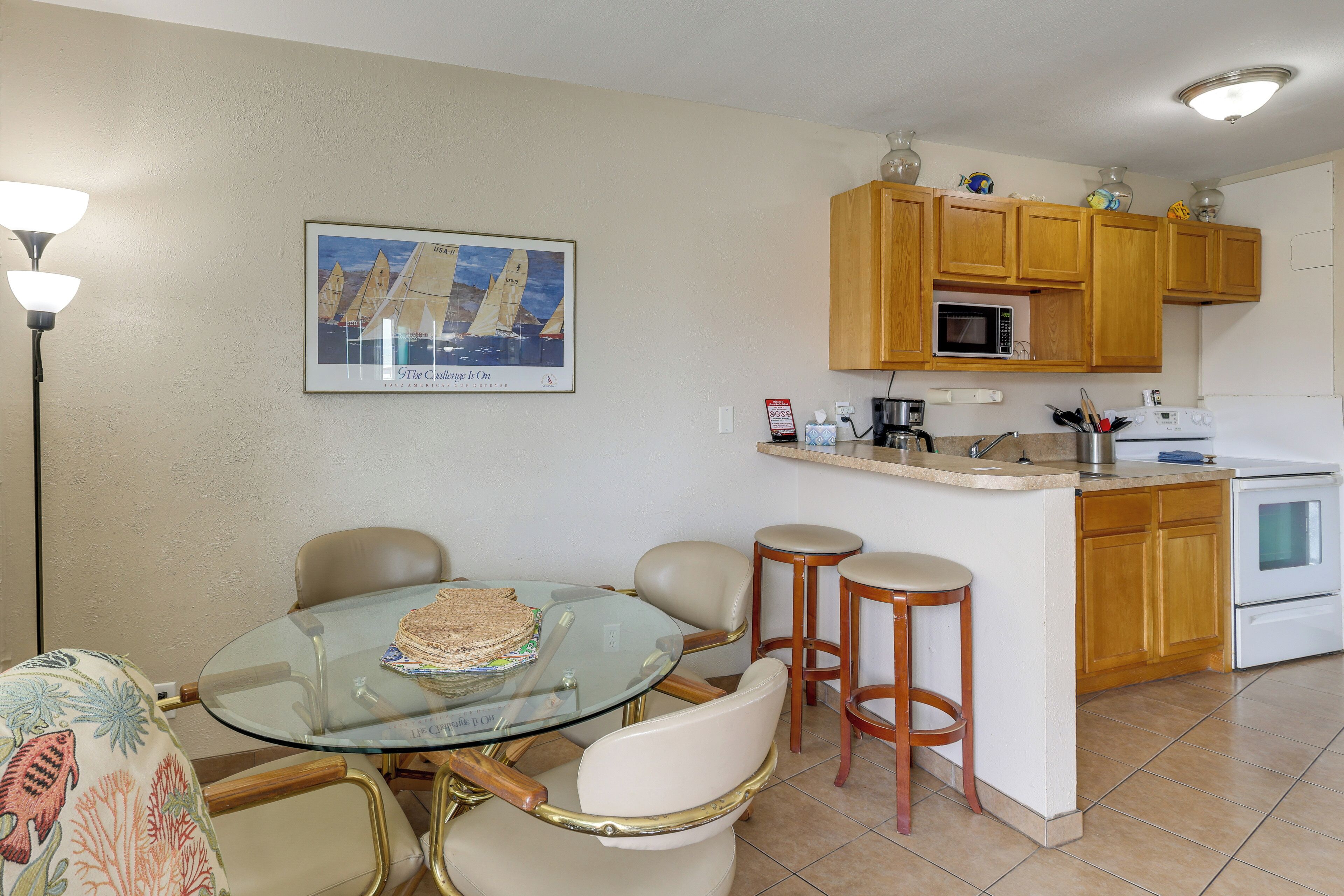 A kitchen with wooden cabinets, a microwave, a stove, and a glass dining table with chairs.