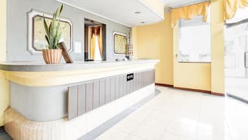 A reception area with a counter, a potted plant, a framed picture, and a sign with 'OYO' on it.
