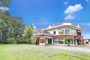 A two-story building with a red and white facade, a small annex with a tiled roof, and a paved courtyard.