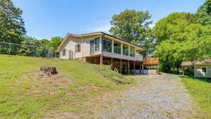 A two-story house with a covered porch, a gravel driveway, and a fenced yard.