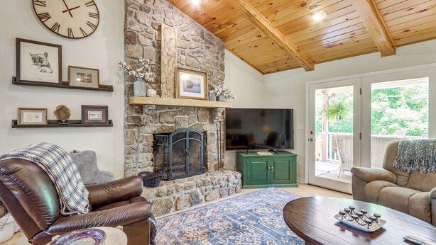 A living room with a stone fireplace, leather sofa, and a television.