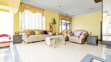 A living room with two sofas, a glass coffee table, and a red chair.
