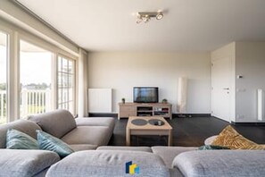 Uma sala de estar moderna com um sofá, uma mesa de centro e uma televisão.
