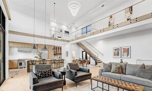 A spacious living area with a high ceiling, a staircase, and a kitchen in the background. - Spacious 4-bedroom house in charming Superior  Modern Home with AC (Superior)