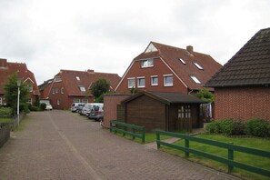 A residential street with brick houses, a paved walkway, and parked cars. - Holiday apartment with 1 bedroom (Norderney)