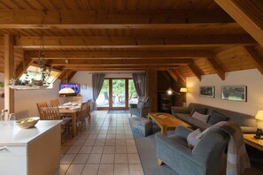 Ein Innenraum mit Essbereich, Sofa, Kamin und Blick durch eine Glastür.
