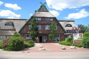 Ein traditionelles Gebäude mit einem steilen Satteldach, Backsteinwänden und einer symmetrischen Fassade.