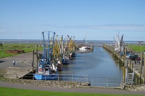Ein Yachthafen mit vertäuten Booten entlang eines schmalen Wasserwegs, umgeben von grünen Flächen und einem klaren Himmel.