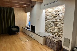 Ein modernes Wohnzimmer mit Steinwand, Flachbildfernseher, Korbwäsche und Holzboden.