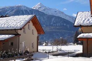 Ein schneebedeckter Berg mit einem Chalet im Vordergrund.