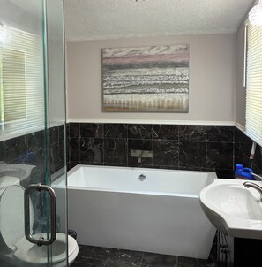 Ein Badezimmer mit Badewanne, Duschkabine, Toilette und Waschbecken.