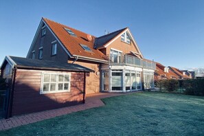 Ein zweistöckiges Haus mit geneigtem Dach, Ziegelaußenwand und einem großen Glasfenster.