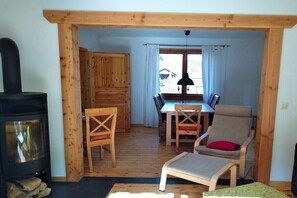 Ein Holzinterieur mit Kamin, Esstisch, Stühlen und einer Couch.
