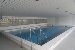 Ein Schwimmbecken mit Metallgeländern, gefliesten Wänden und einem Fliesenboden.