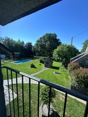 A backyard with a swimming pool, a stone structure, and a well-maintained lawn.