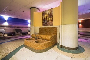 Un área de spa con un jacuzzi, sillones de descanso y un cuadro colgado en la pared.