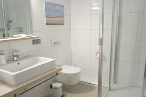 Un baño moderno con un lavamanos grande, inodoro y cabina de ducha de vidrio.