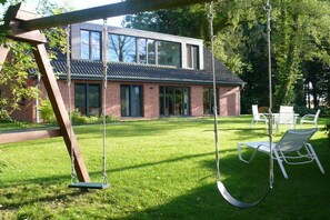 Ein modernes Haus mit Schaukel und Garten, mit Ziegelaußenwand und großem Fensterfront.