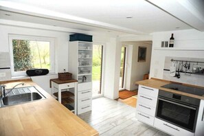 Eine moderne Küche mit Holzausziehtisch, eingebauten Regalen, einer Spüle und einem Backofen.