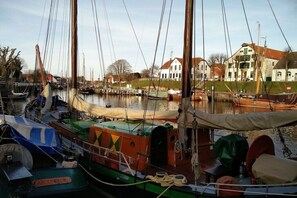 Ein Yachthafen mit vertäuten Booten, ein weißes Gebäude mit rotem Dach und eine Rasenfläche im Hintergrund.