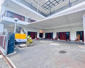 Un edificio de varios niveles con un patio cubierto, bancos de madera y una estatua.