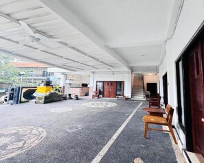 Un espacio al aire libre techado con un conjunto de asientos, una pequeña mesa y una estructura decorativa.