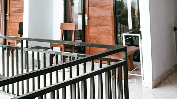 Ein modernes Hotelzimmer mit Balkon, großen Fenstern und einer Holztür.