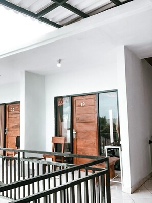 Una habitación de hotel moderna con balcón, ventanas amplias y puerta de madera.