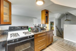 A kitchen with a stove, sink, wooden cabinets, and a countertop.