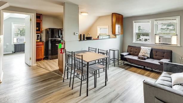 Una cocina moderna con refrigerador, estufa y comedor con sillas y una mesa.