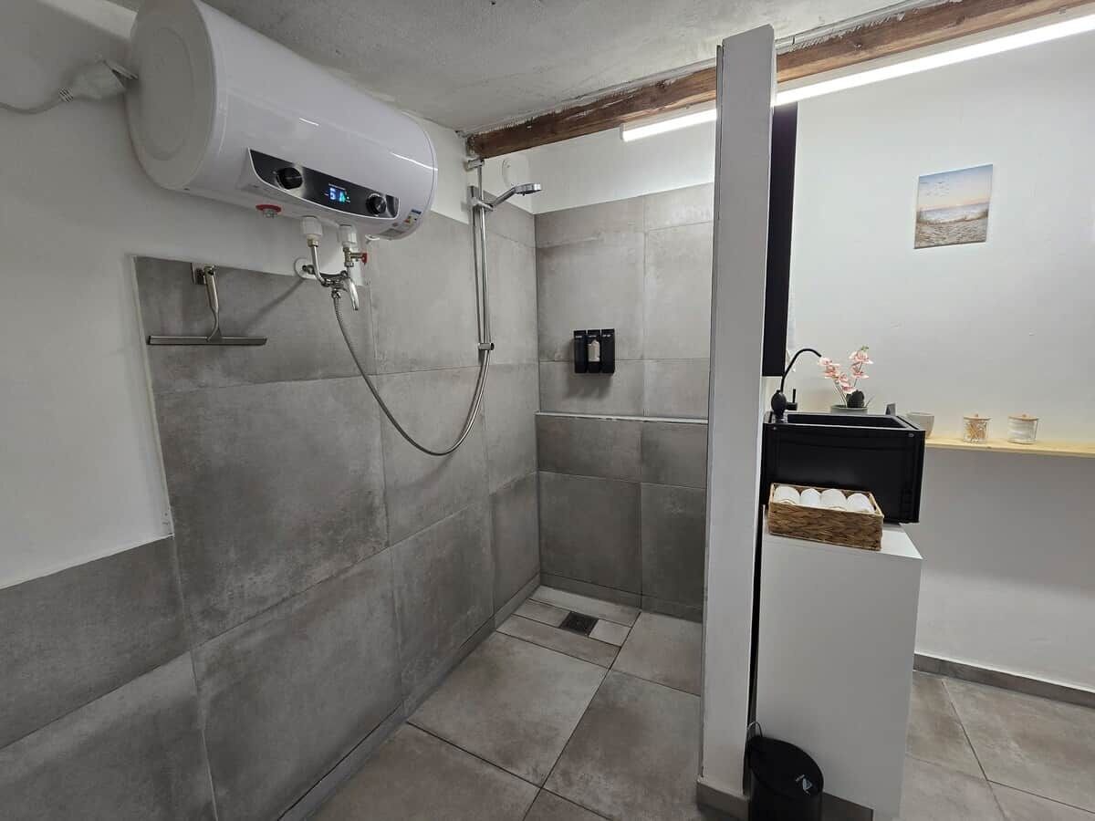 A shower with a digital display, a towel rack, and a small shelf with decorative items.