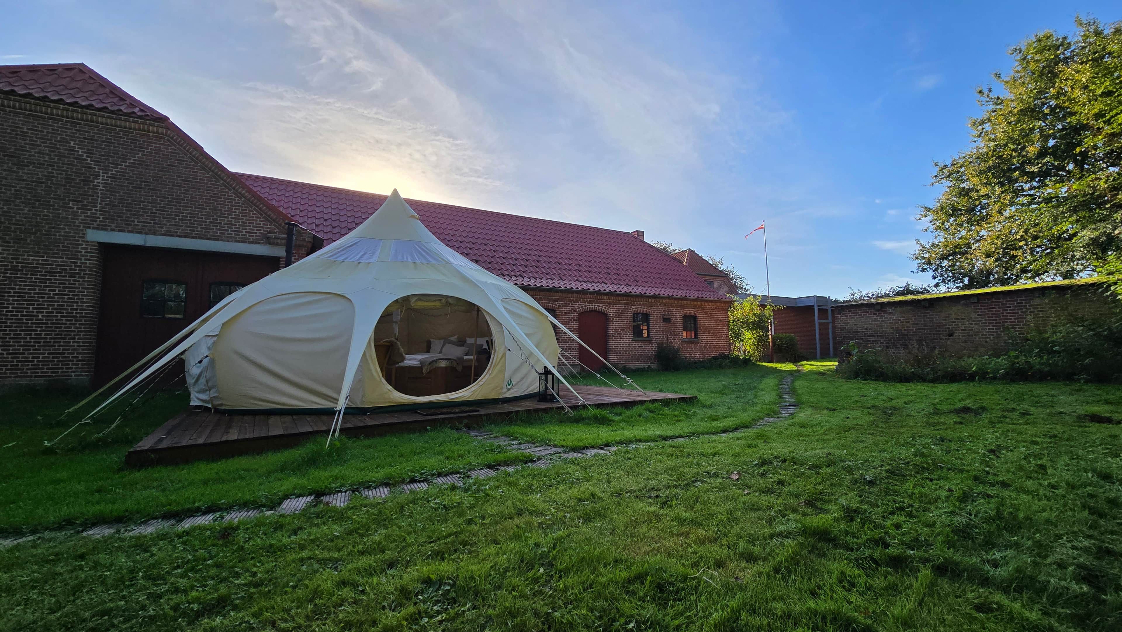 A tent set up in a grassy area with a brick building in the background.