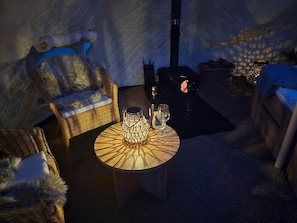 Une pièce chaleureuse avec une table ronde, des chaises en osier, un verre et une bougie.