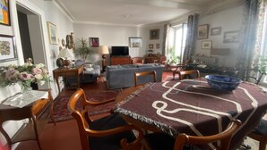 Un comedor con una mesa, sillas, un sofá, un televisor y una araña.