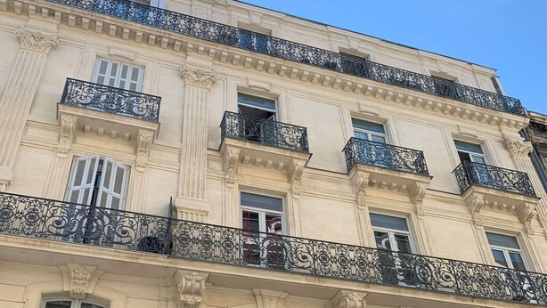 Un edificio de varios pisos con balcones decorativos y detalles arquitectónicos clásicos.