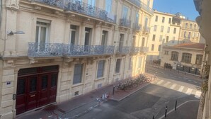 Un edificio de varios pisos con balcones decorativos, una puerta roja y bicicletas estacionadas en la acera.