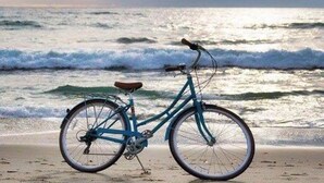 Una bicicleta en la playa con olas de fondo.