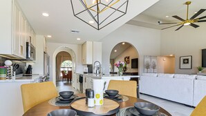 A modern kitchen with white cabinets, a dining area with a wooden table and chairs, and a living room with a sofa and TV. - Mtn-View Fountain Hills Oasis w/ Private Pool! (Fountain Hills)
