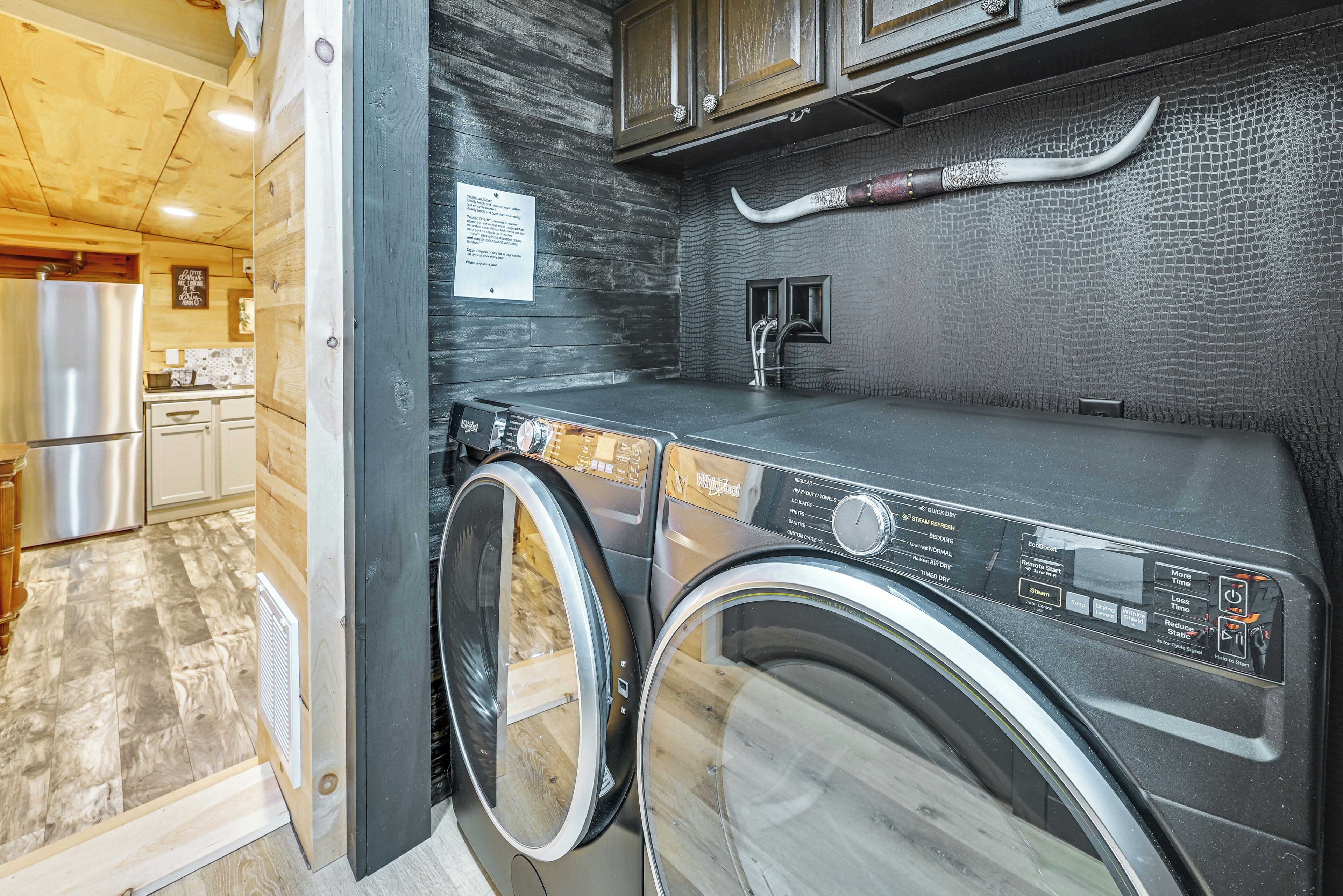 Un espace buanderie compact comprenant un lave-linge, un sèche-linge et un évier.