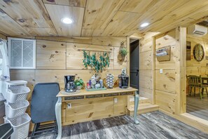 A wooden interior with a counter, chairs, baskets, and a hanging plant.