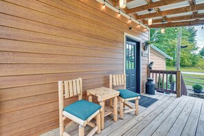 Una terraza de madera con una mesa, sillas, una puerta y barandilla.