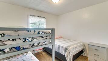 Een slaapkamer met stapelbedden, een raam, een bureau en een kledingkast.