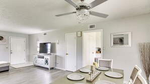 Un comedor con una mesa preparada para cuatro personas, un ventilador de techo y una araña.