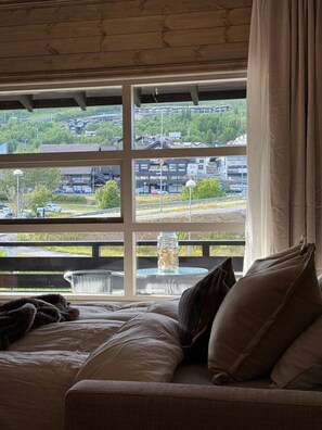 Une chambre avec une grande fenêtre, un lit et une vue sur la ville.